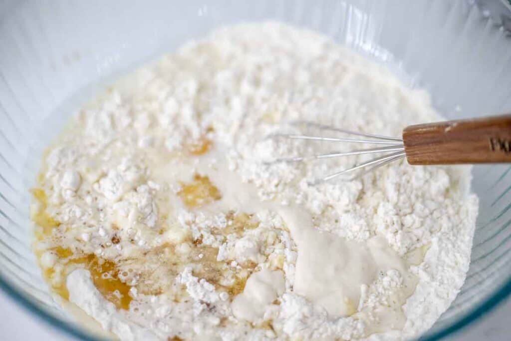 Dry ingredients and wet ingredients for sourdough discard pancakes in a large bowl with a whisk.