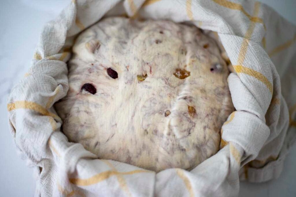 Bread dough in a towel lined bowl.