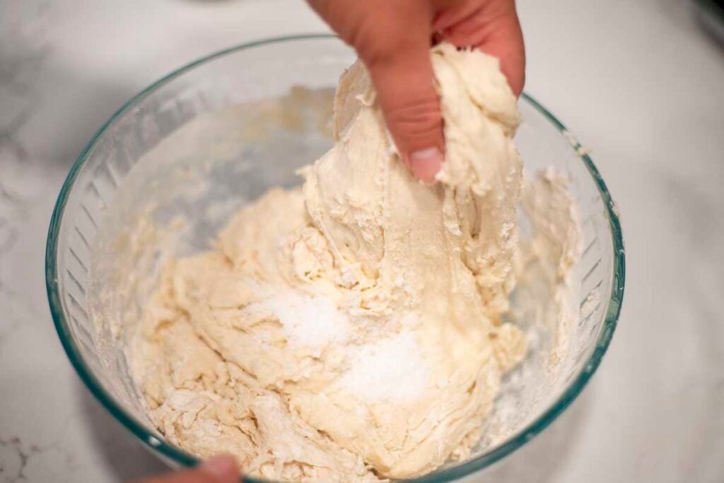 Hand grabbing dough to perform stretch and folds.