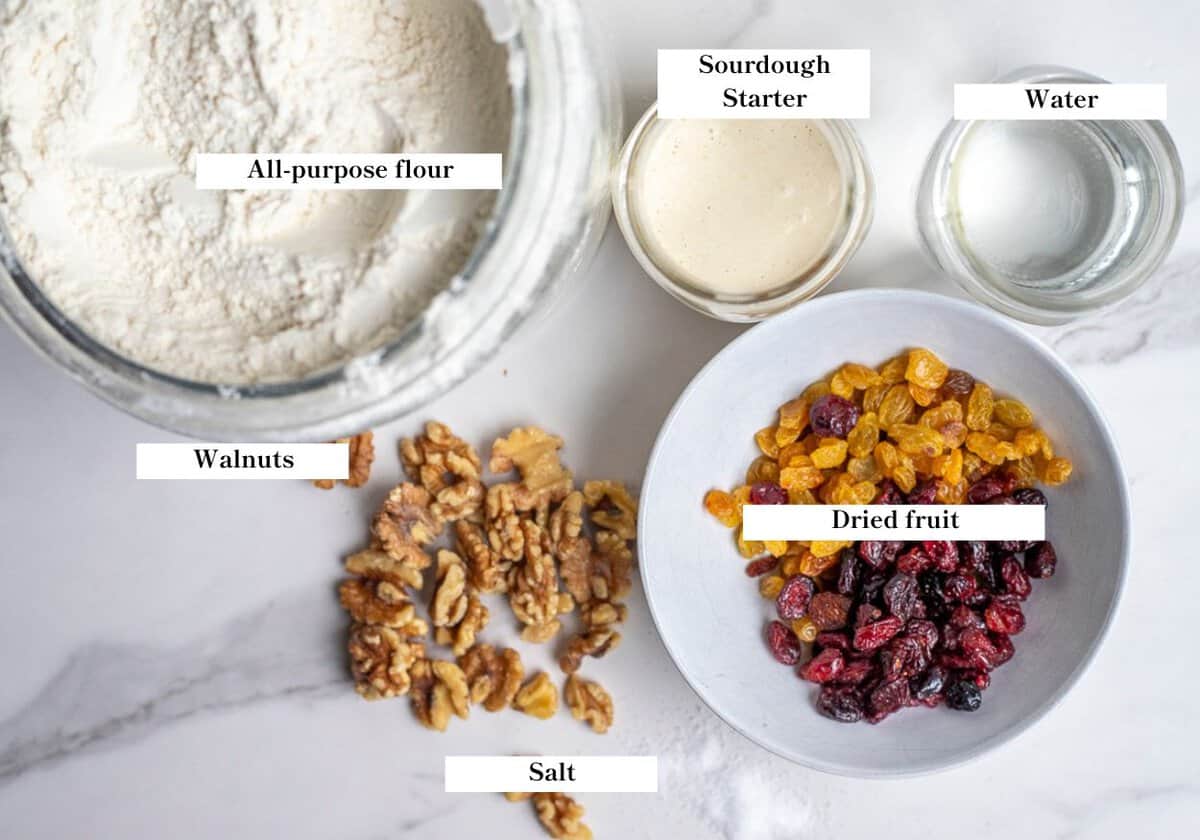 Ingredients for fruit and nut sourdough bread in containers on a countertop.