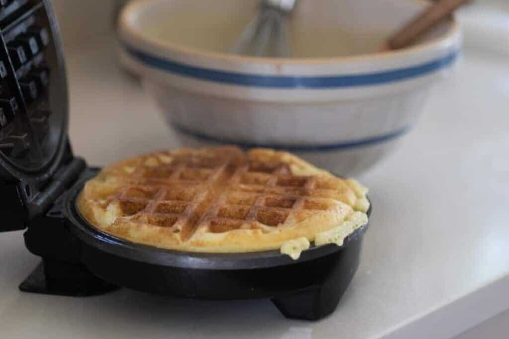 A fully cooked waffle in a waffle maker.