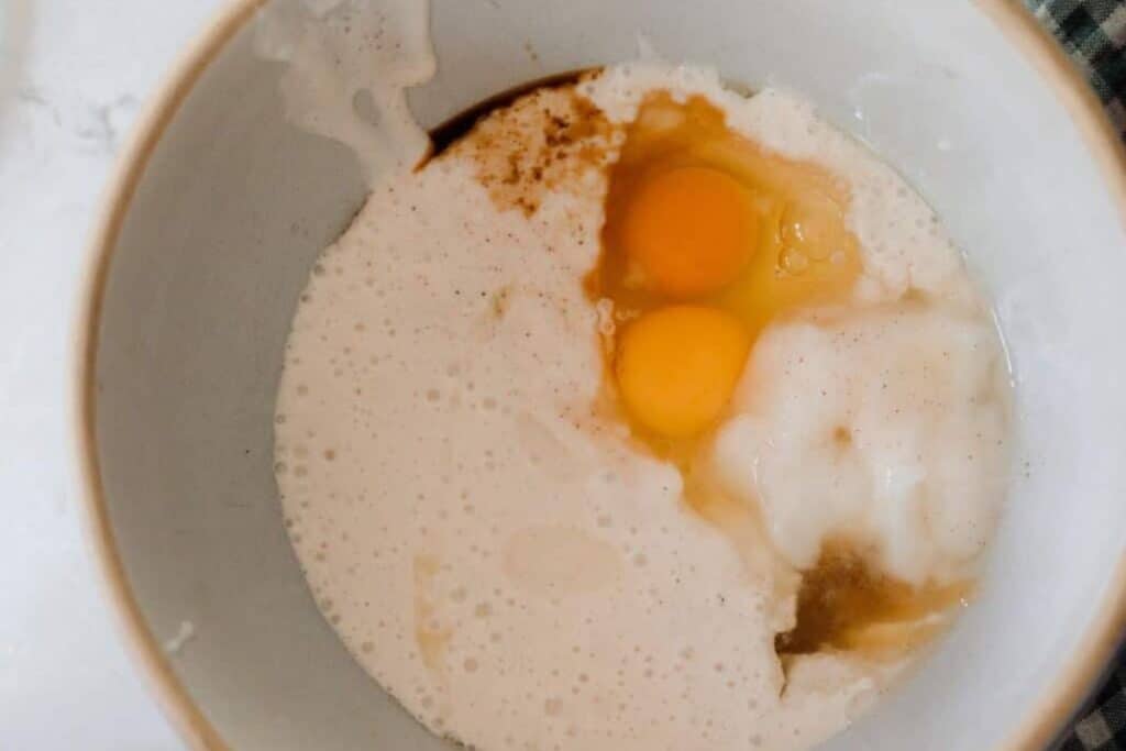 Bowl containing sourdough starter, eggs, oil, salt, cinnamon, honey and vanilla for waffle batter.