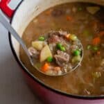 A ladle removing beef stew from the dutch oven.