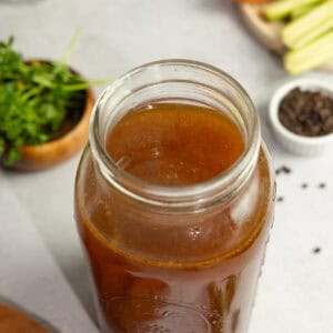 bone broth in a mason jar with ingredients surrounding.