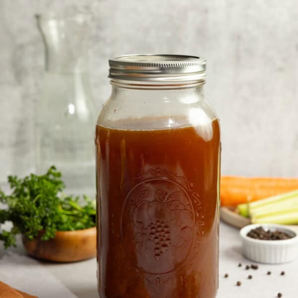 Bone broth in a half gallon mason jar with ingredients surrounding the jar.