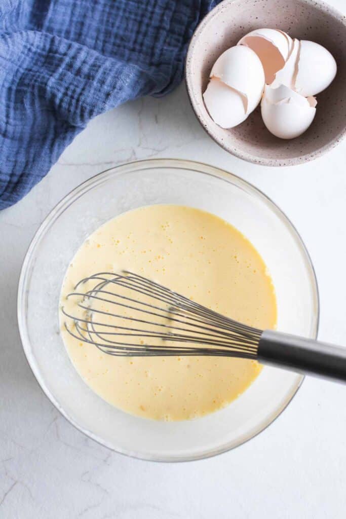 Eggs and sourdough starter in a bowl with a whisk.