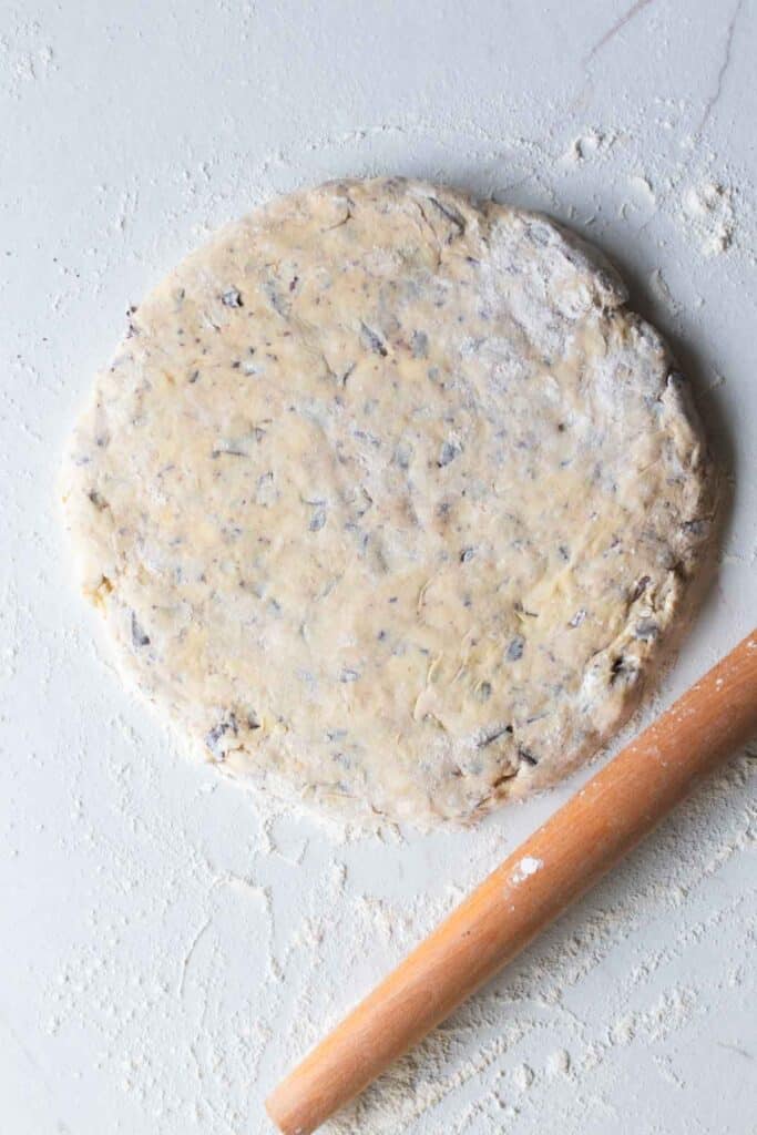 Dough rolled out into a circle with a rolling pin next to it.