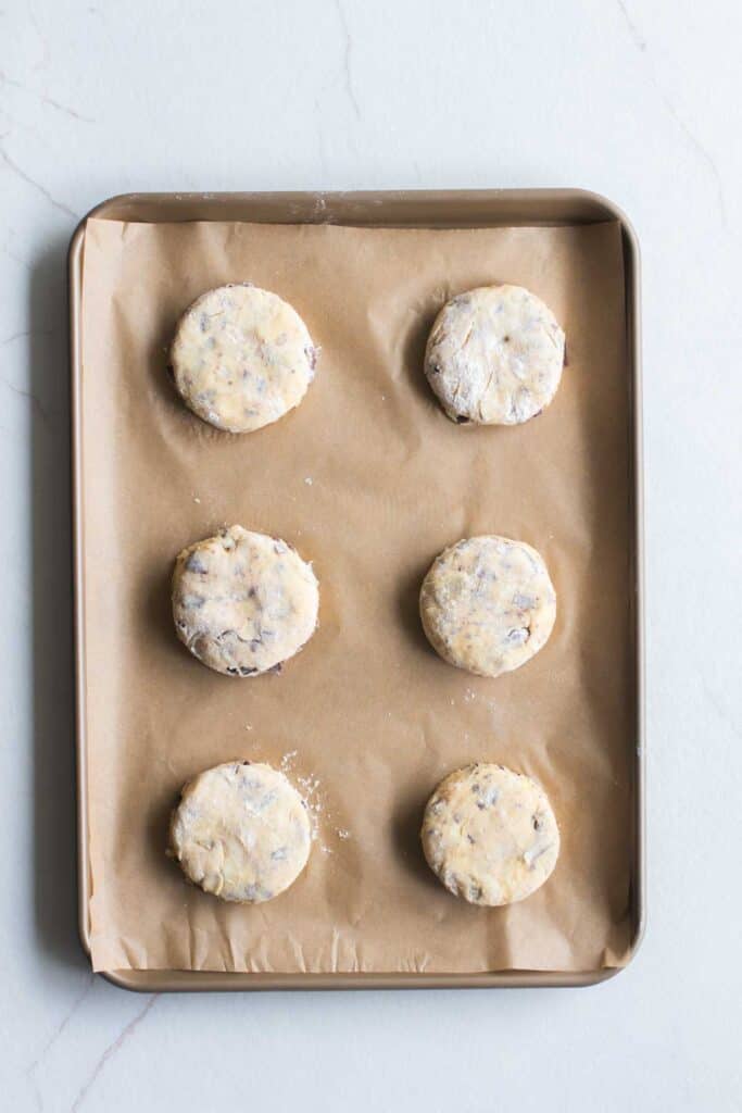 Unbaked scones on a parchment paper lined baking sheet.