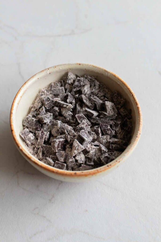 Chopped chocolate in a bowl, coated with flour.