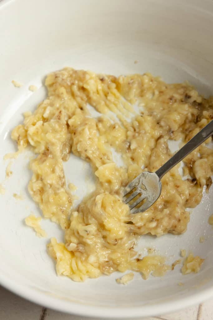 Banana mashed with a fork in a bowl.