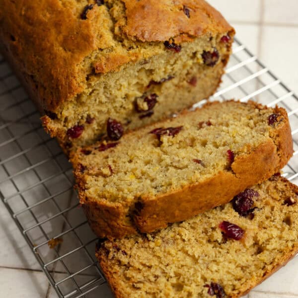 A loaf of cranberry banana bread with two pieces sliced.