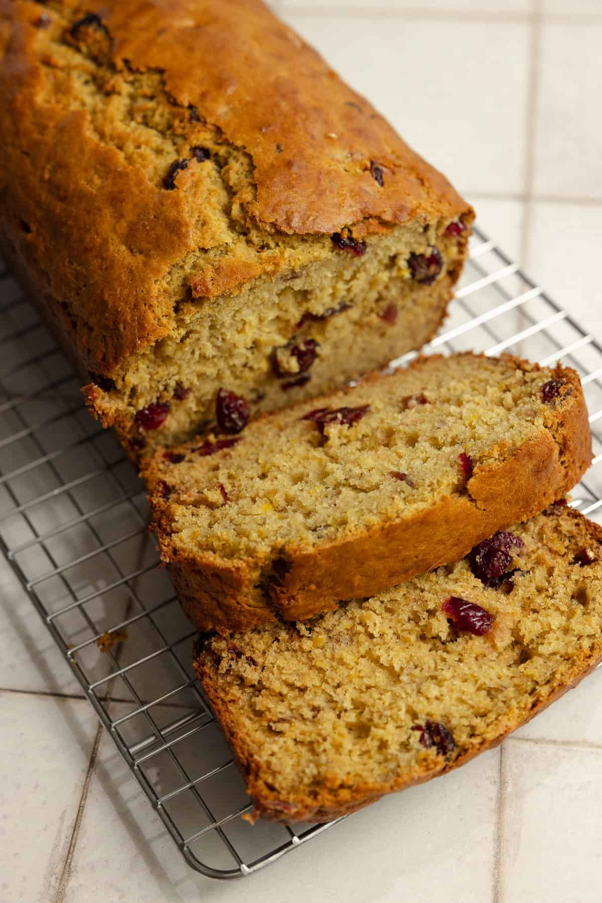 A loaf of cranberry banana bread with two pieces sliced.