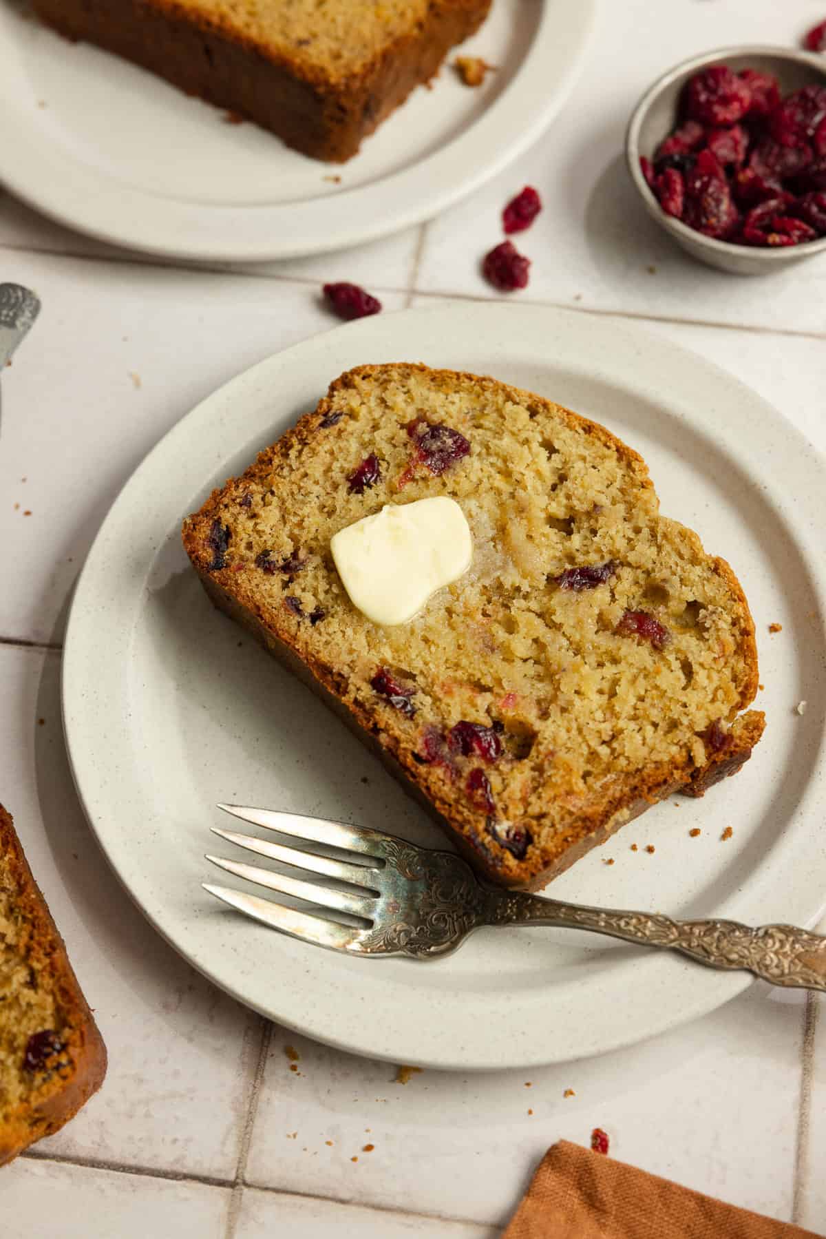 A slice of banana bread on a white plate with a fork.