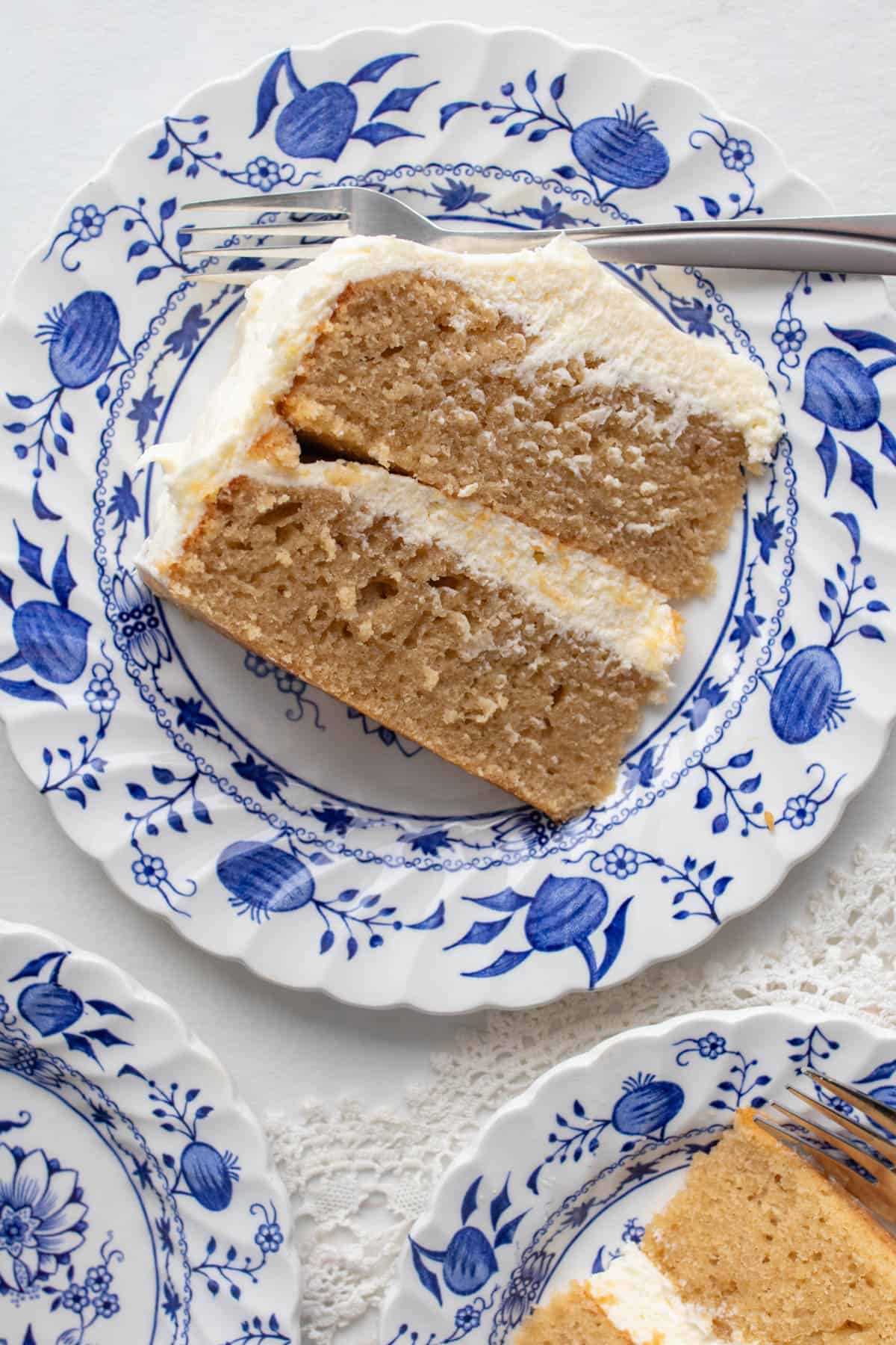 A slice of earl grey cake with cream cheese frosting on a blue floral plate.