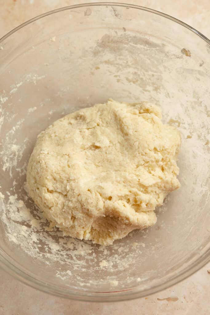 A dough ball formed from mashed potatoes and other ingredients in a clear bowl.