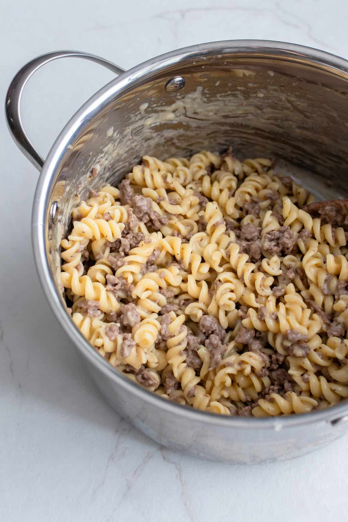 Pasta and beef mixed together in a pot.