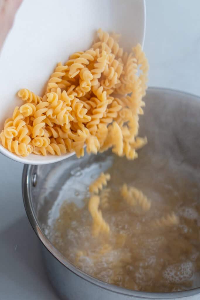 A large draining spoon taking out pasta from boiling water.