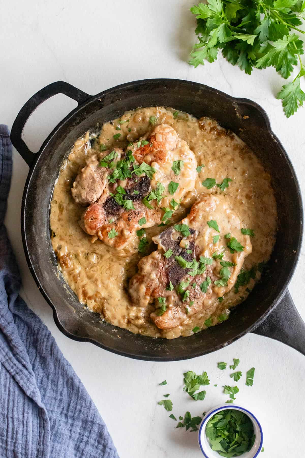 Pork steaks in a creamy onion gravy in a cast iron skillet.