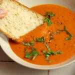 A slice of bread dipped into a bowl of soup.