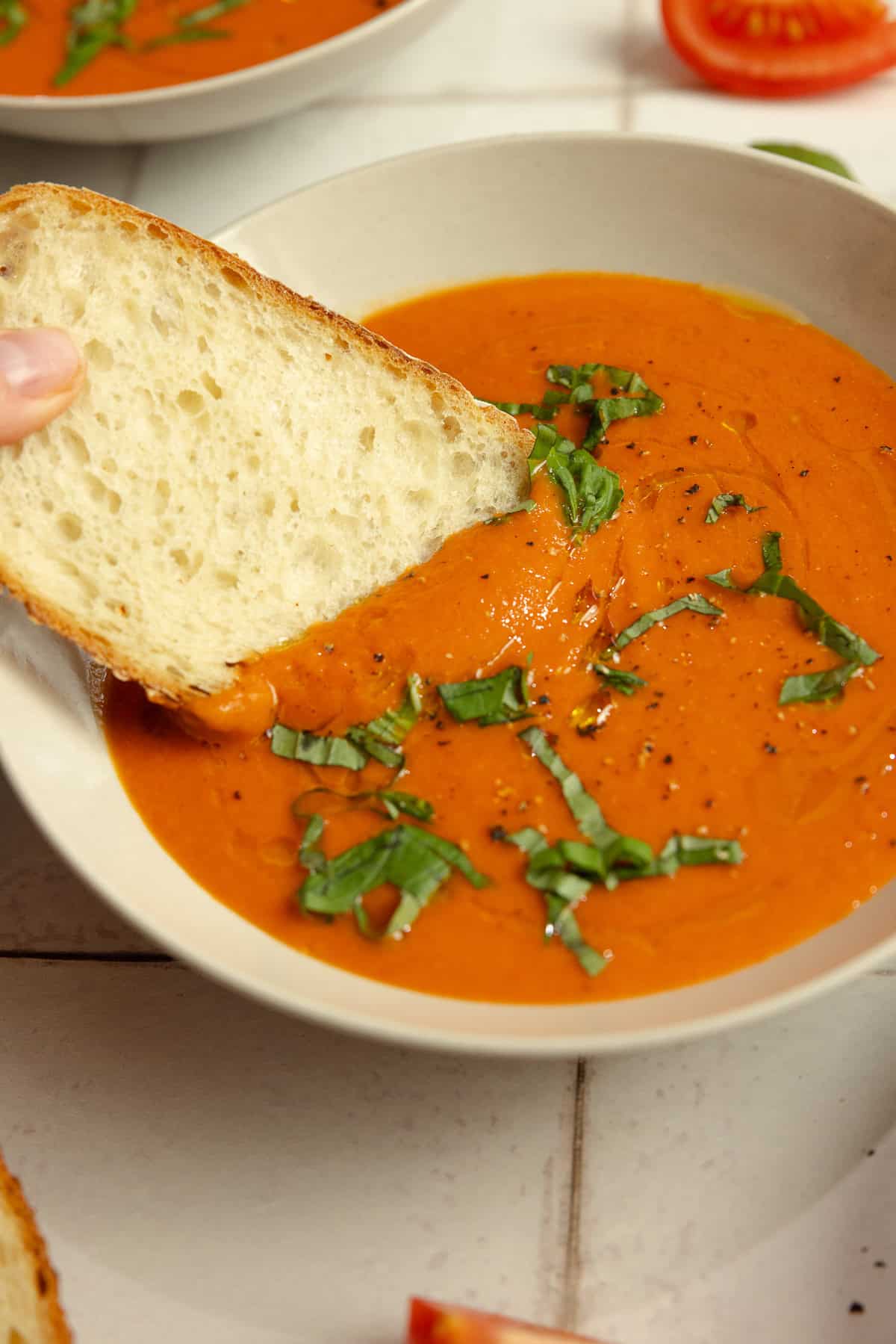 A slice of bread dipped into a bowl of soup. 