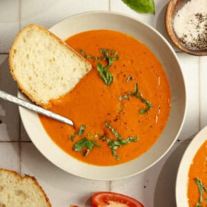 A bowl of soup with a slice of bread and a spoon sticking out.