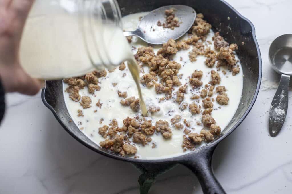 Milk added to a cast iron pan of browned meat.