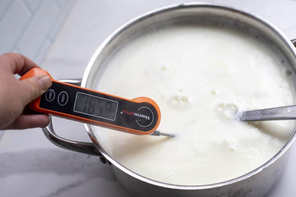 Heating milk up with a thermometer in the pot of milk.