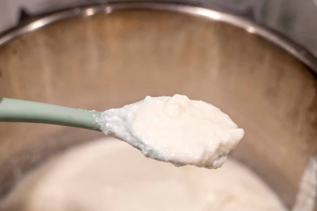 A spoon scooping yogurt out of the instant pot.