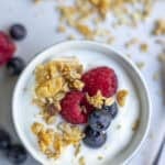 A bowl of yogurt topped with granola and fruit.