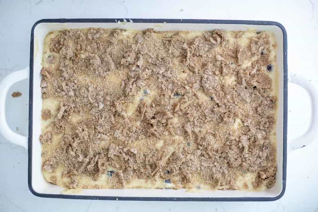 Unbaked sourdough blueberry coffee cake topped with crumble in a baking dish.