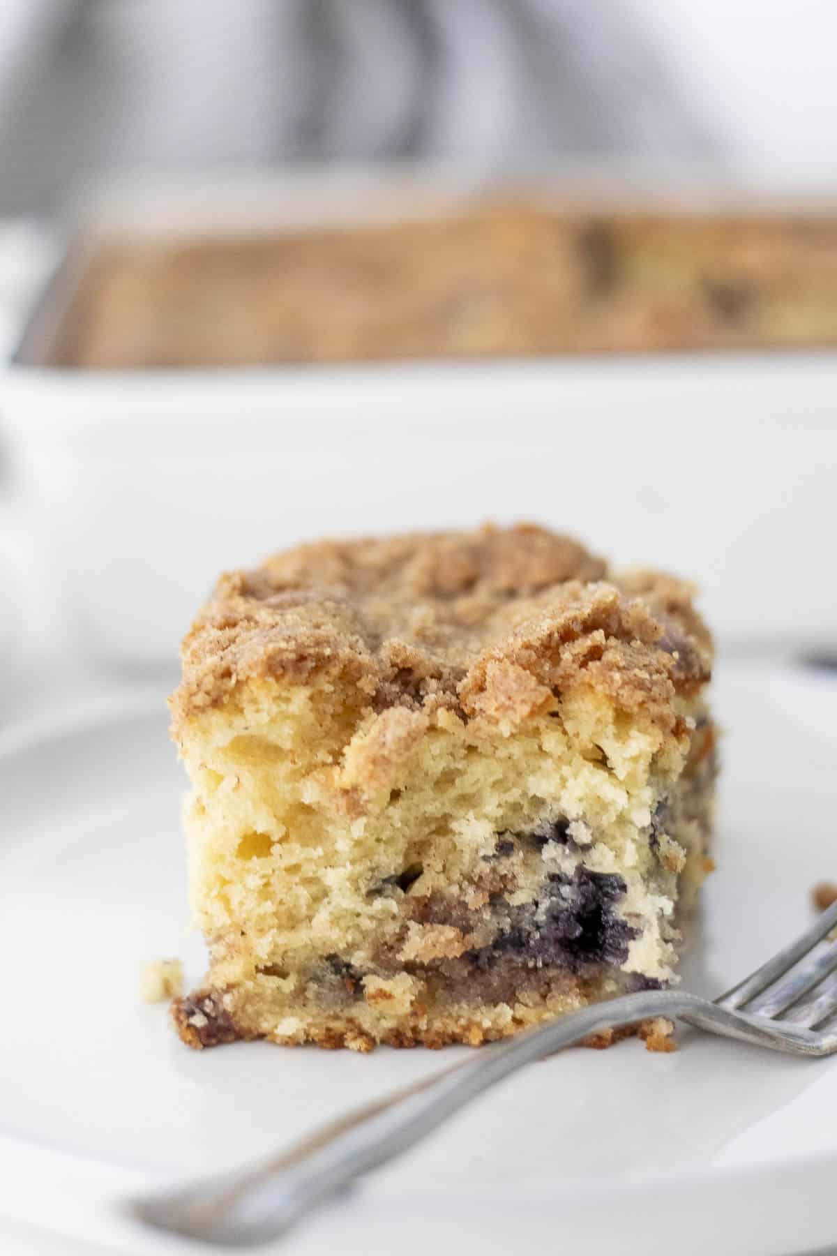 Close up picture of sourdough blueberry coffee cake on a plate with a fork.