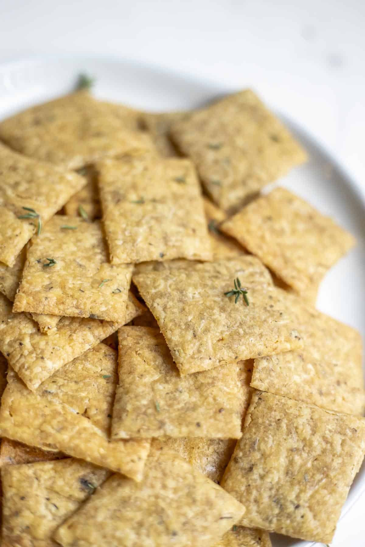 A plate of sourdough crackers topped with fresh thyme.