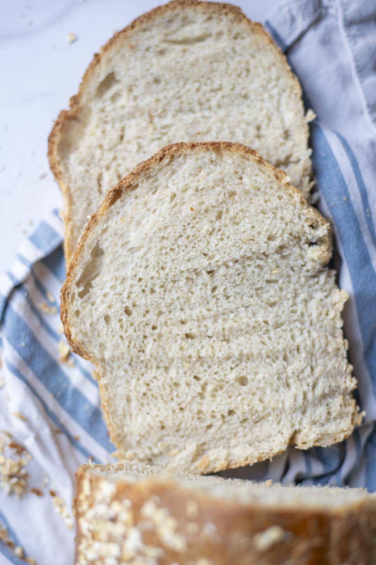 overhead photo of two slices of sourdough oatmeal bread laying on a towel.