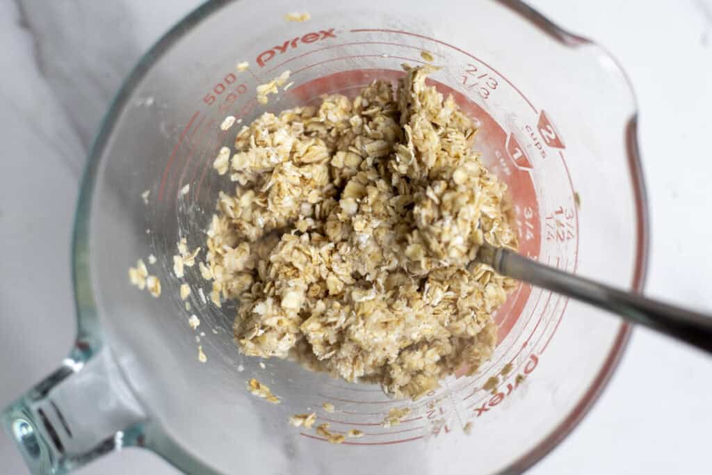 oats soaking in water in a measuring cup.