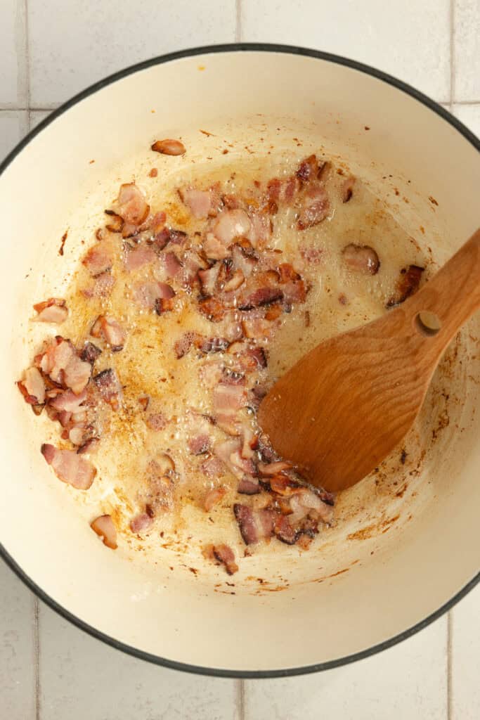 Bacon pieces in the bottom of a large Dutch oven. 