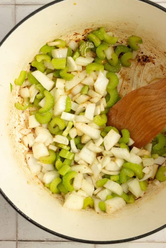 Veggies sauted in a dutch oven with a wooden spoon. 