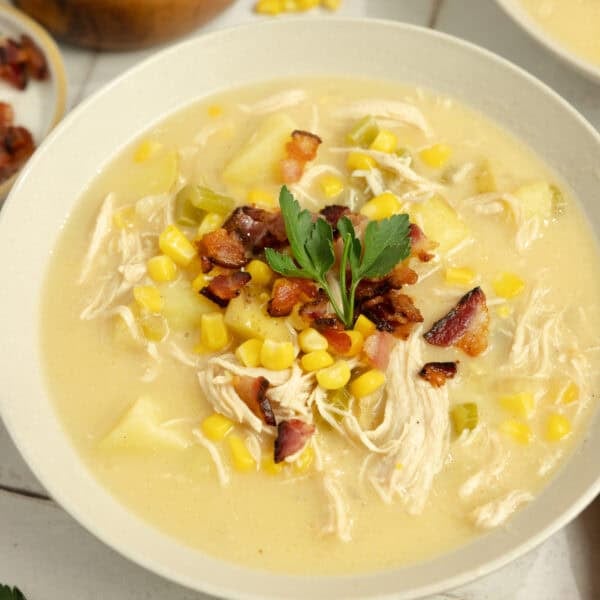 A bowl of chicken corn chowder with a garnish.