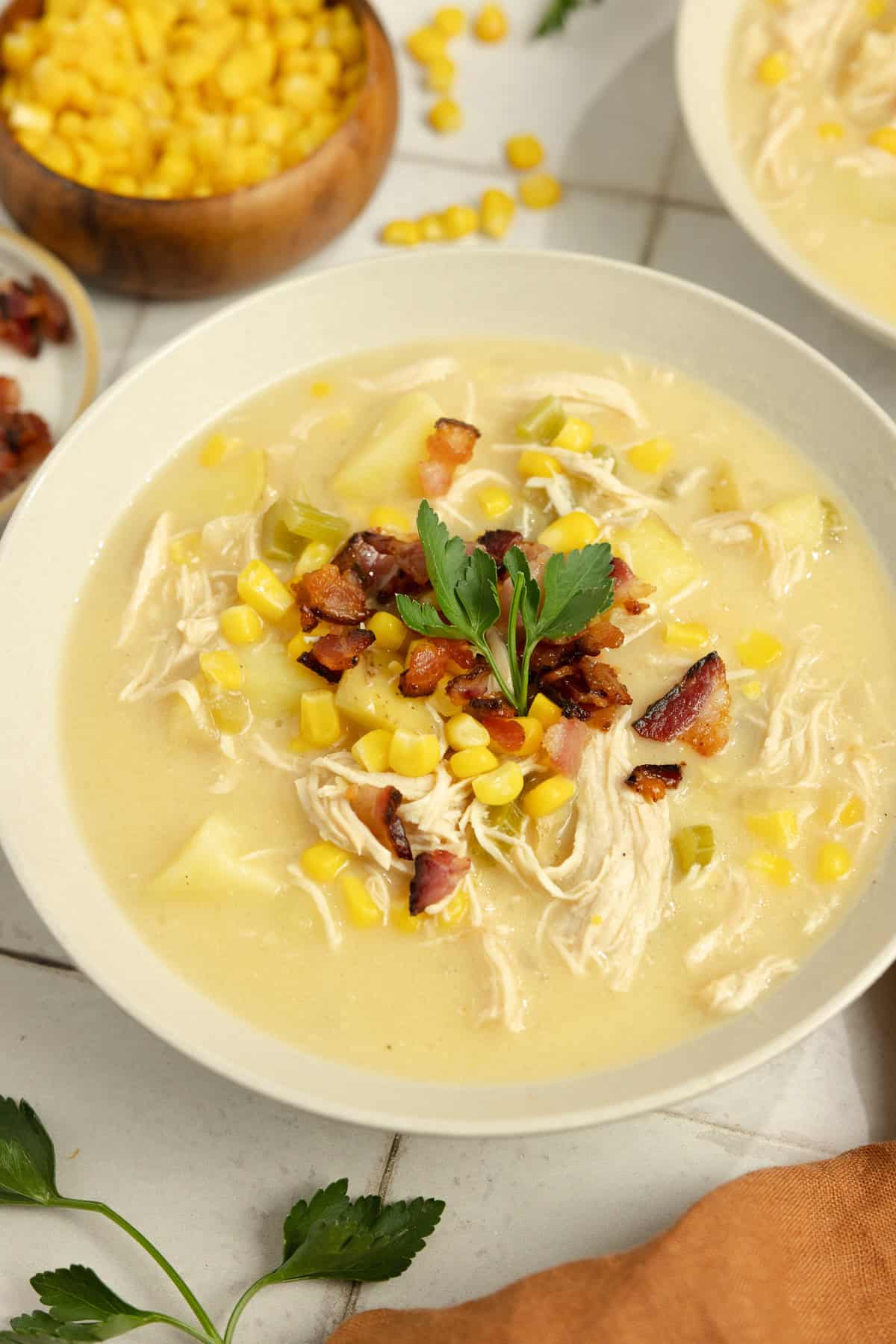 A bowl of chicken corn chowder with a garnish.