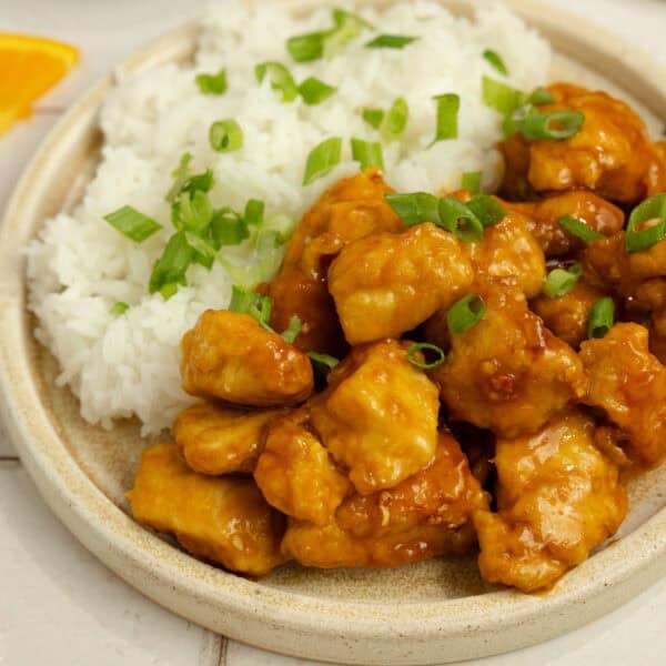 A plate of orange chicken with rice.