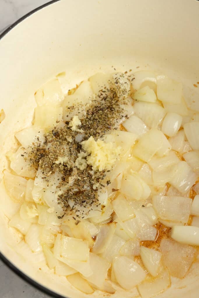 Herbs added to a Dutch oven with onions.