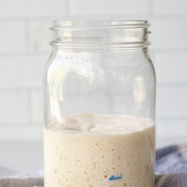 Bubbly sourdough starter in a mason jar on a towel.