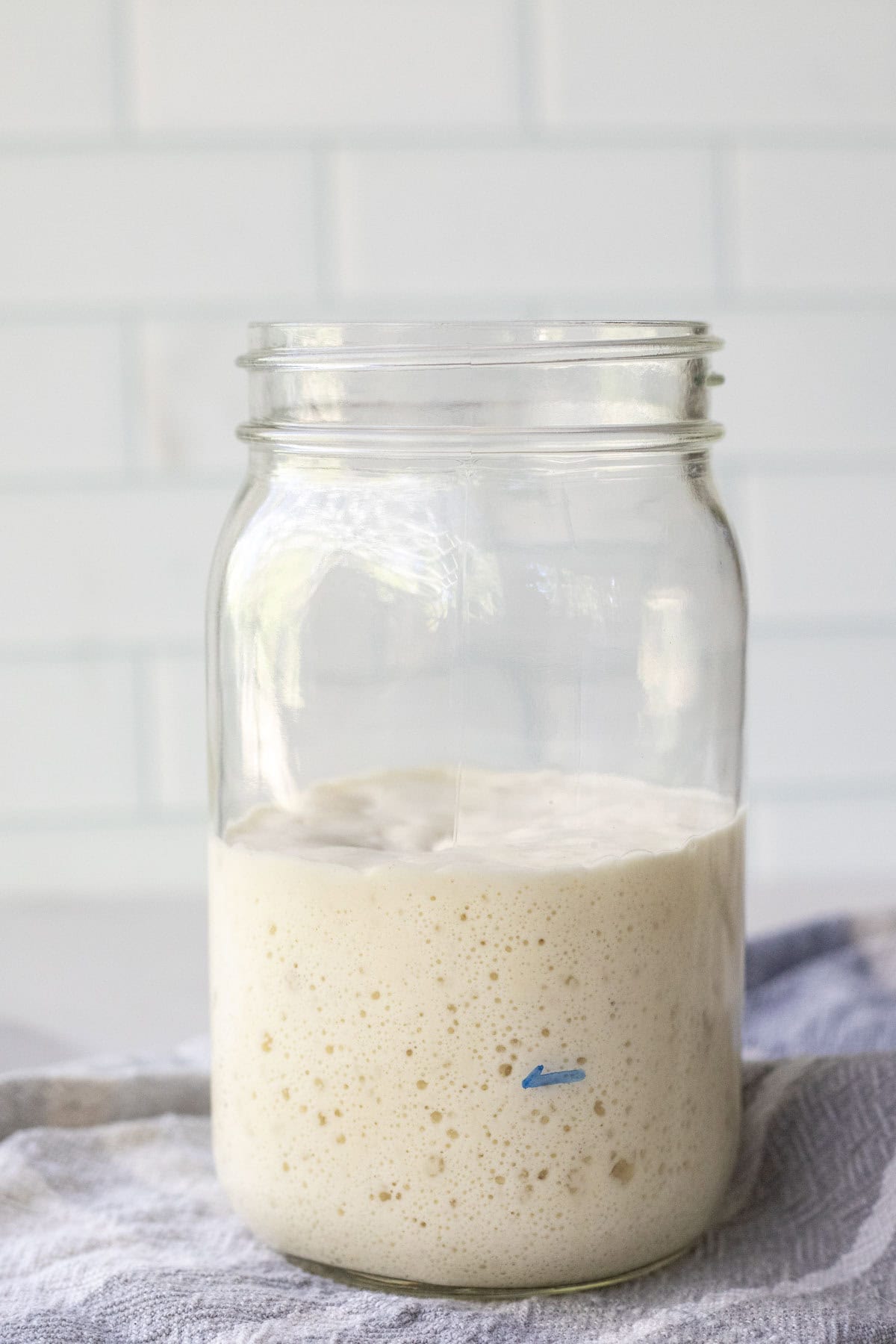 Bubbly sourdough starter in a mason jar on a towel.