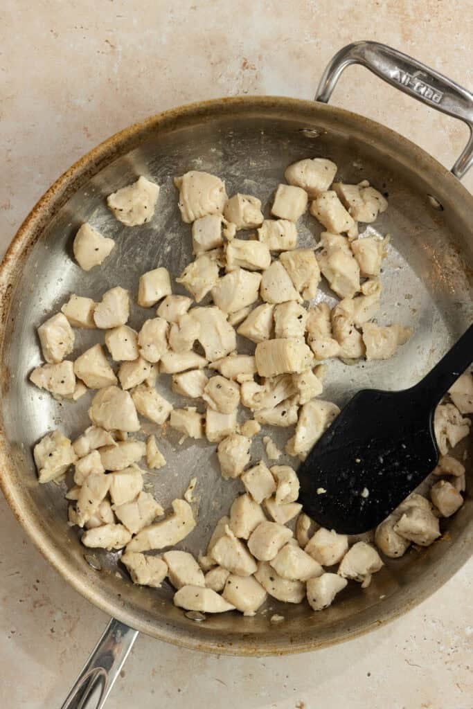 Cubed chicken in a skillet with a spatula. 